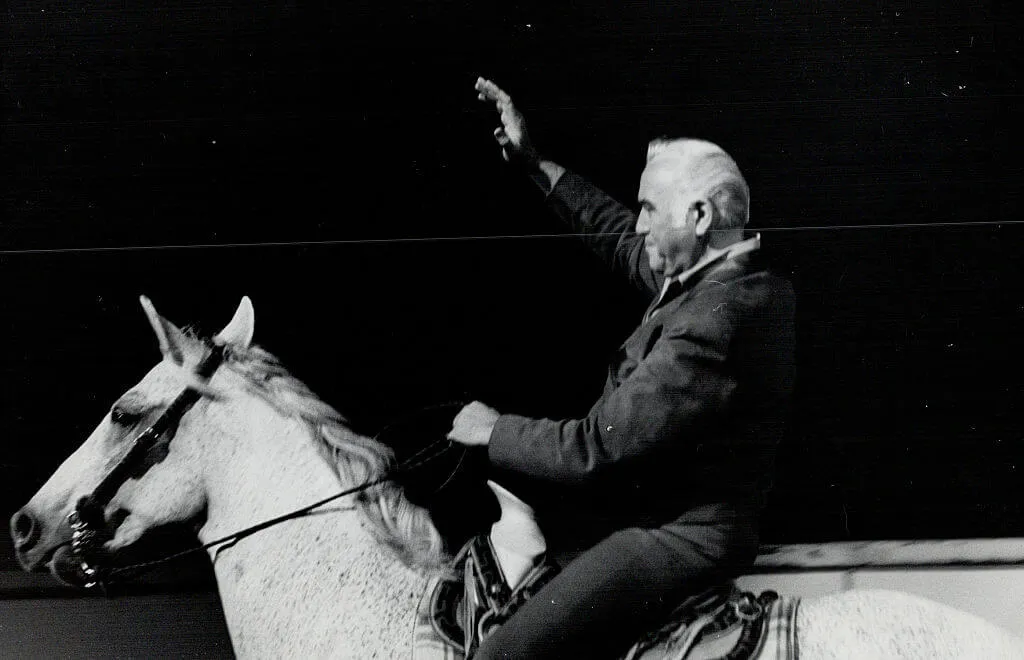 Lorne Greene rides horse and waves