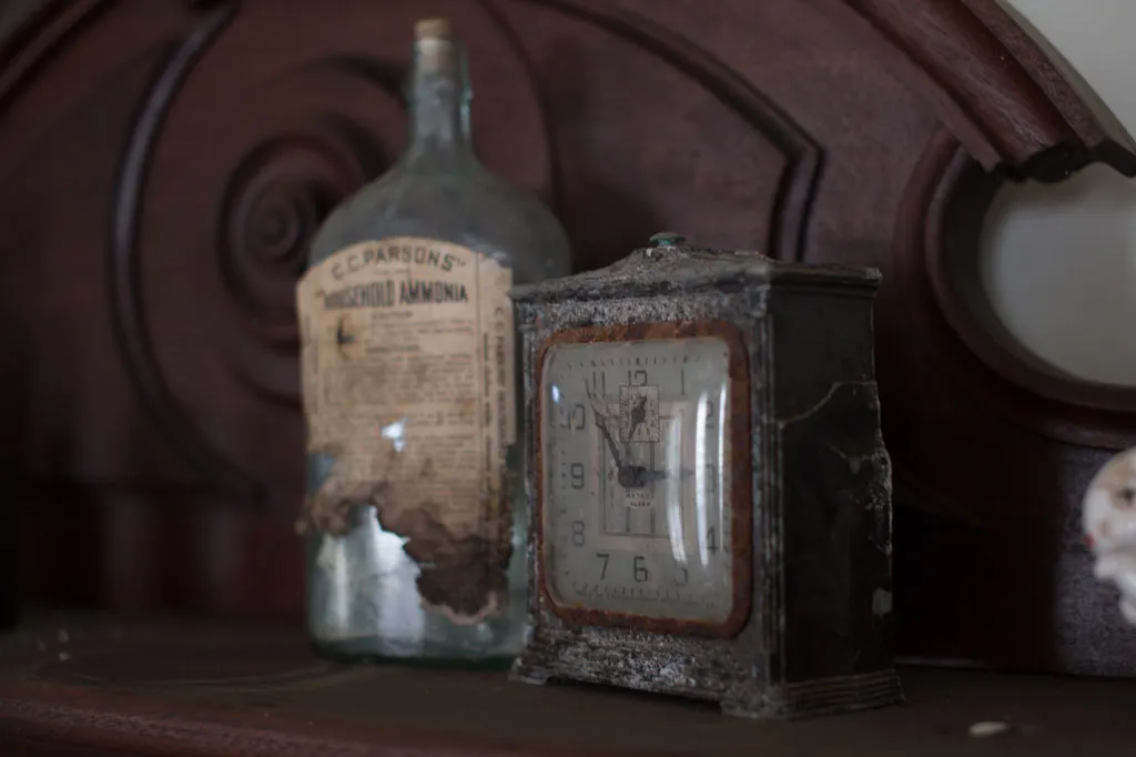 a clock and a bottle on the mantle
