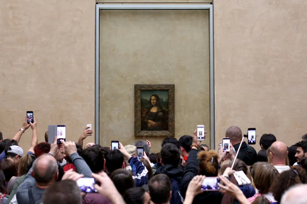 Visitors take pictures of 'La Joconde', a 1503-1506 oil on wood portrait of Mona Lisa by Leonardo Da Vinci, at the Louvre Museum in Paris,