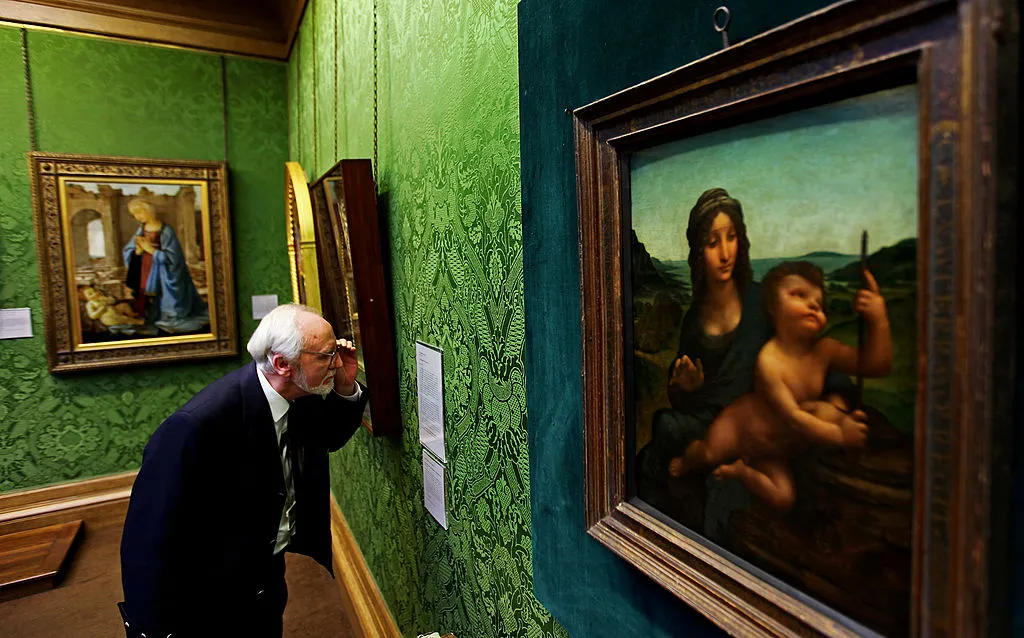 Joe Hay, security guard at the National Gallery of Scotland, stands beside the Leonardo da Vinci painting 'Madonna Of The Yarnwinder'