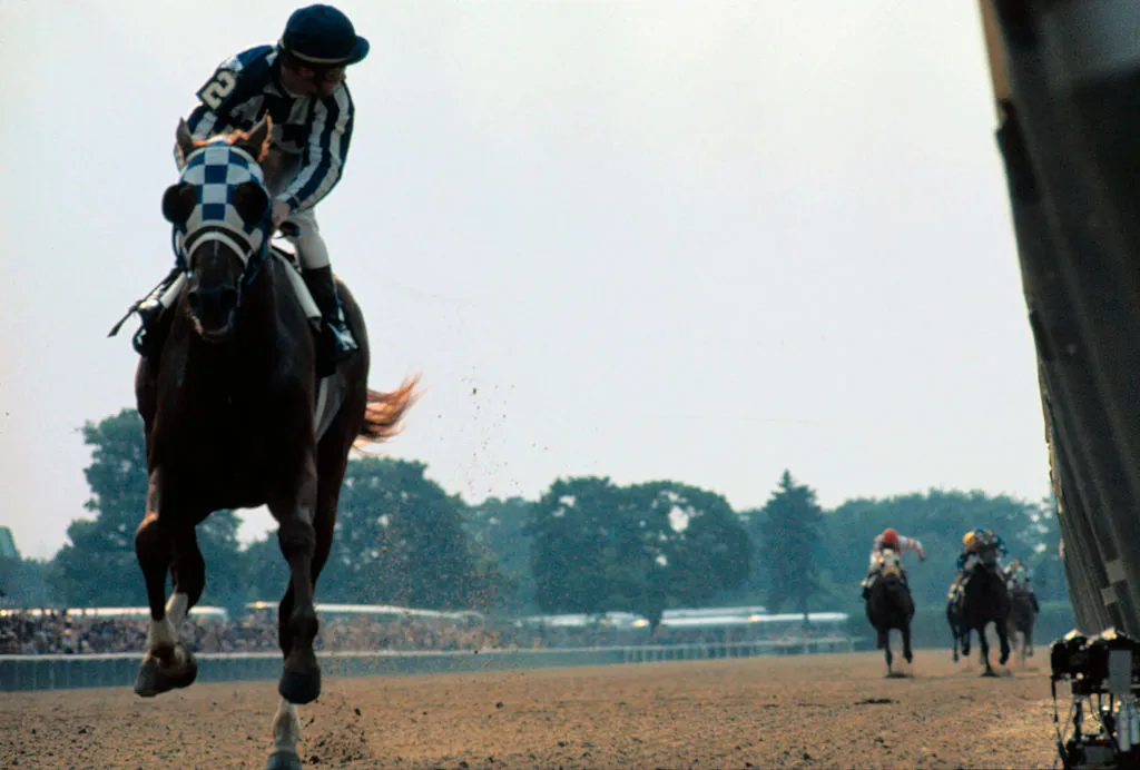 GettyImages-515108596 The field is so far behind, jockey Ron Turcotte has to turn in the saddle to look for it as he guides Secretariat to victory in the Belmont Stakes.