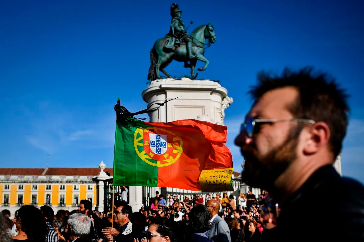 A man waves a Portuguese flag with black stripes as a sign of mourning as hundreds of people gather at the Comercio square in Lisbon on October 21, 2017 to protest against the government's response during the recent forest fires in Portugal which killed more than a hundred people.