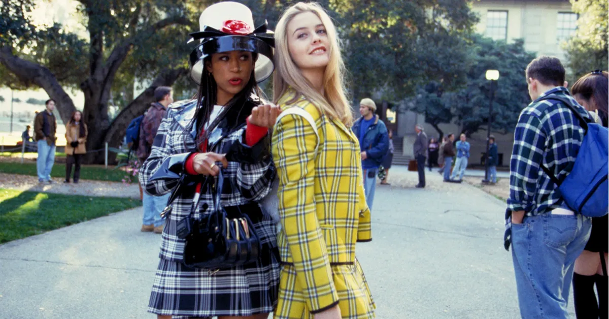 stacey dash and alicia silverstone in plaid outfits in front of a school in clueless