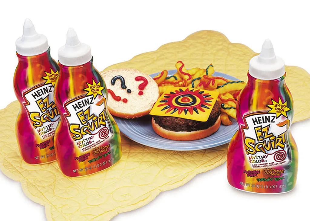 a few bottles of heinz ez squirt mystery color ketchup and a cheeseburger and fries on a placemat