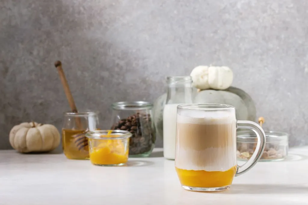 glass of pumpkin spice latte with pumpkin puree, milk foam, and cinnamon