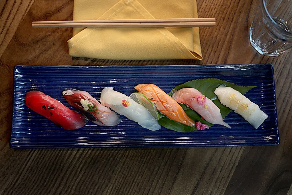 a palette of sushi on a table with chopsticks