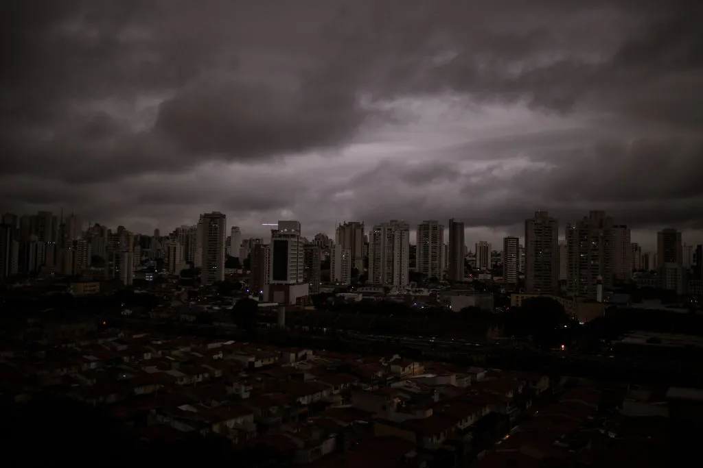 A view of São Paulo's skyscrapers shows dark grey skies over a nearly black city.
