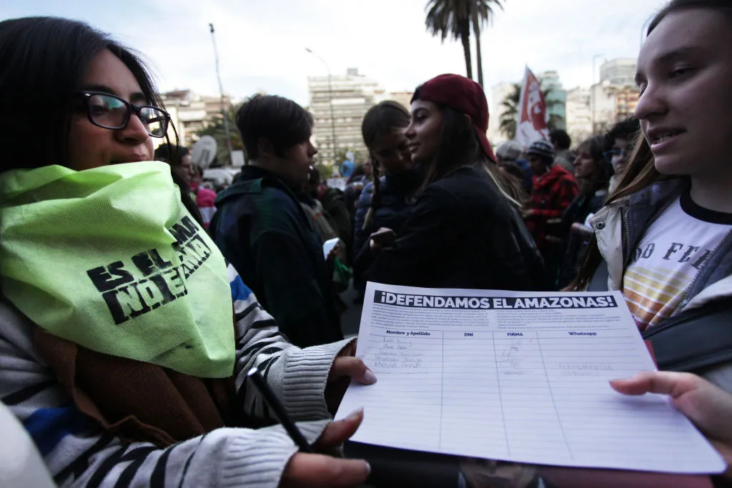 Young ladies in a crowd in Argentina hold a petition that reads 