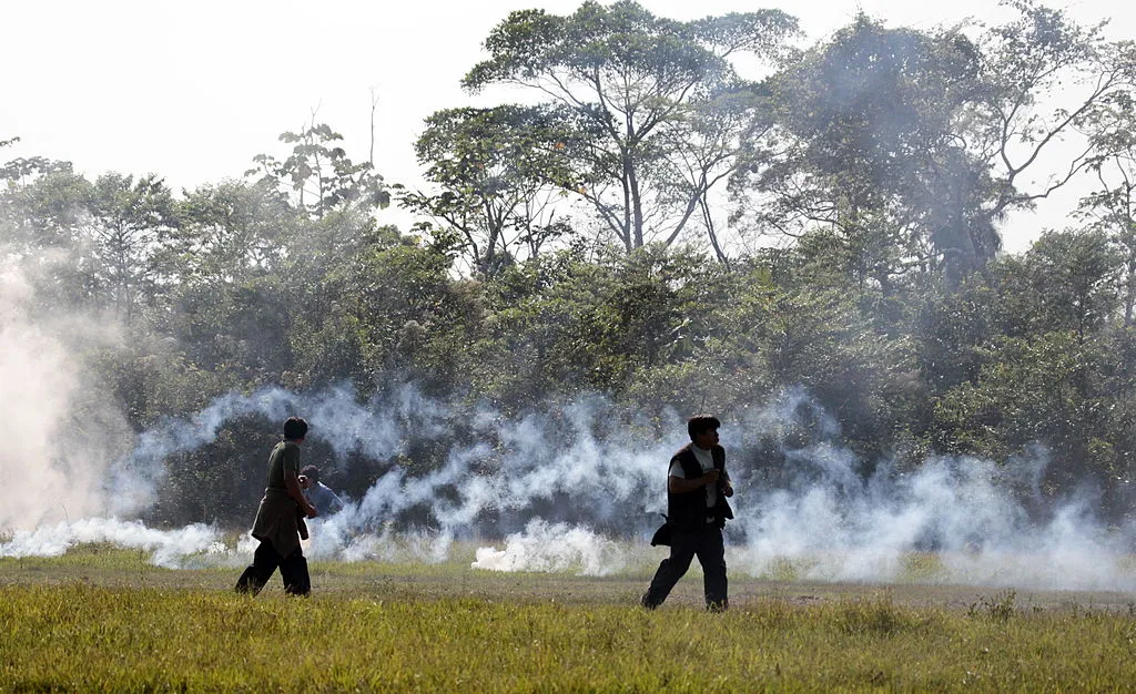Two Bolivian protestors exit the rainforest amongst clouds of tear gas.