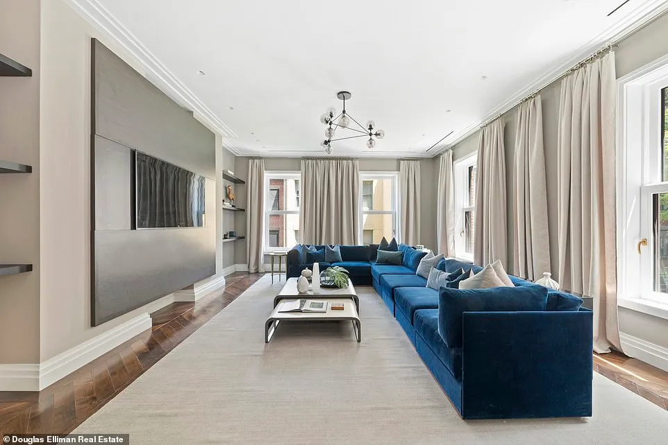 A large, rectangular family room showcases a blue, L-shaped couch to match the L-shape of the windowed walls.