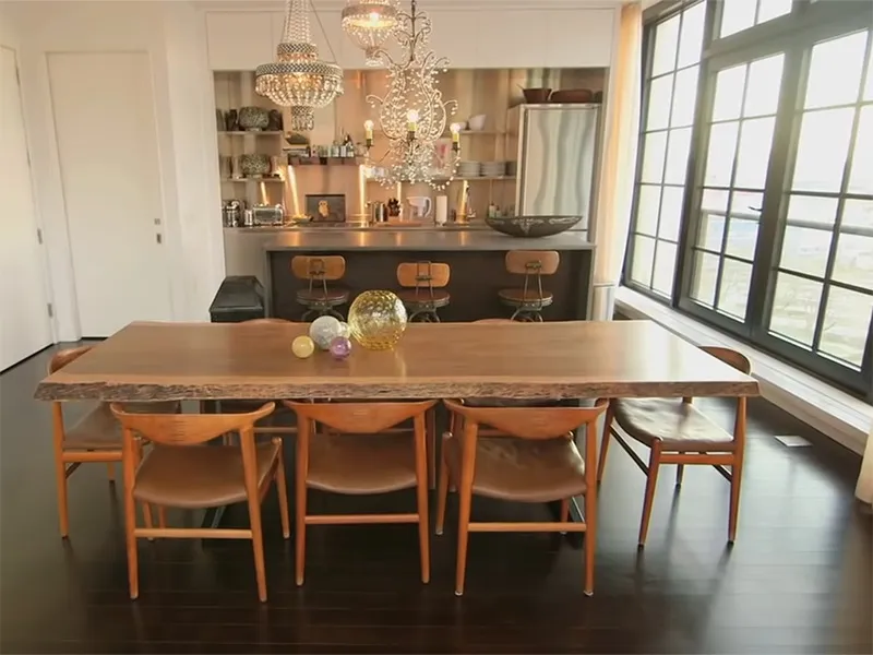 An open dining room-kitchen combination rests beside floor to ceiling windows