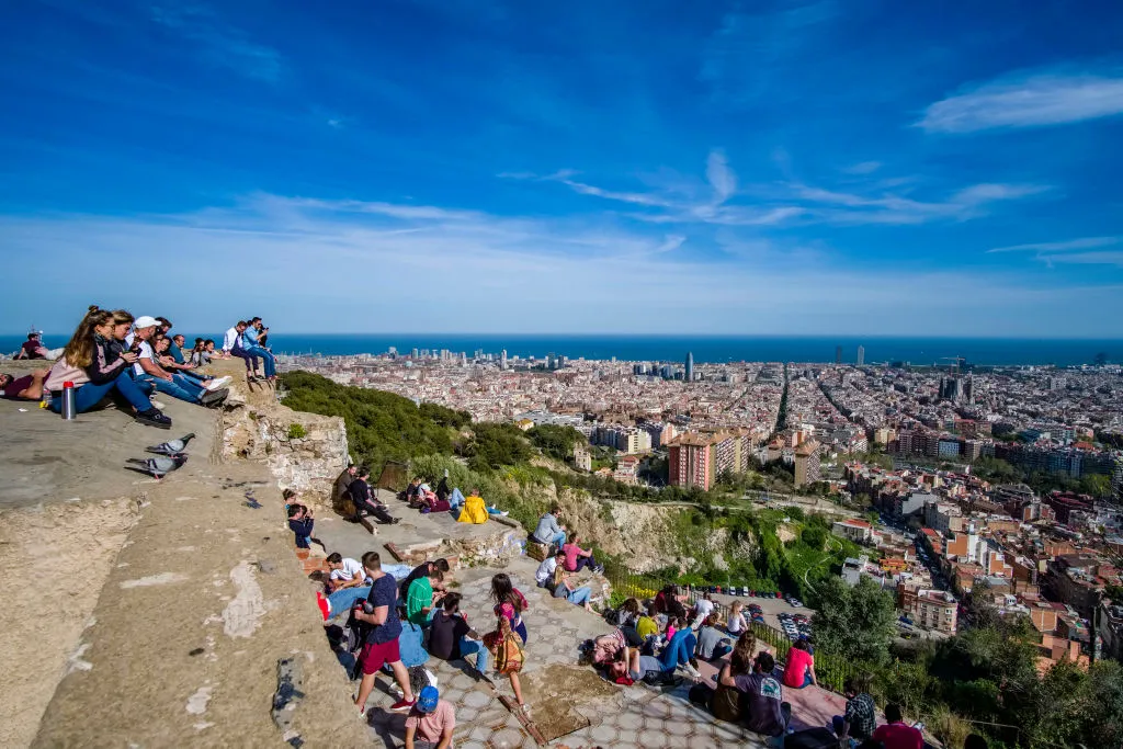 People gather on steps to overlook the aerial view of Barcelona
