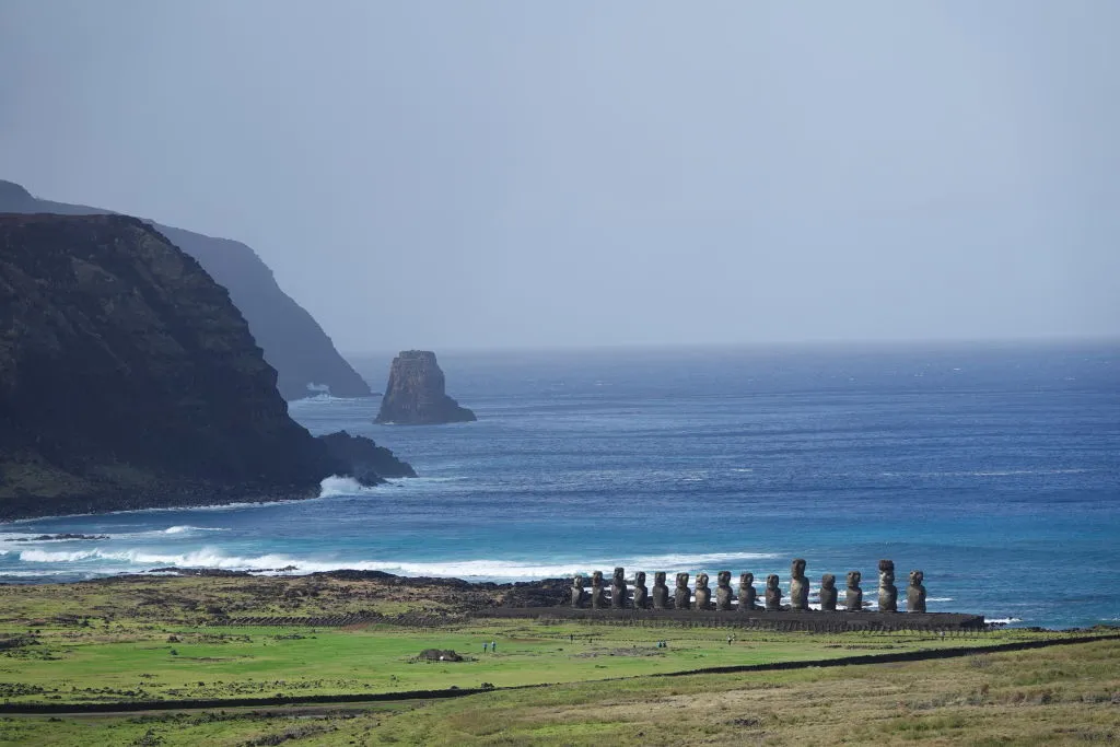 Tourists are barely visible compared to the giant statues of Eastern Island in this faraway photo