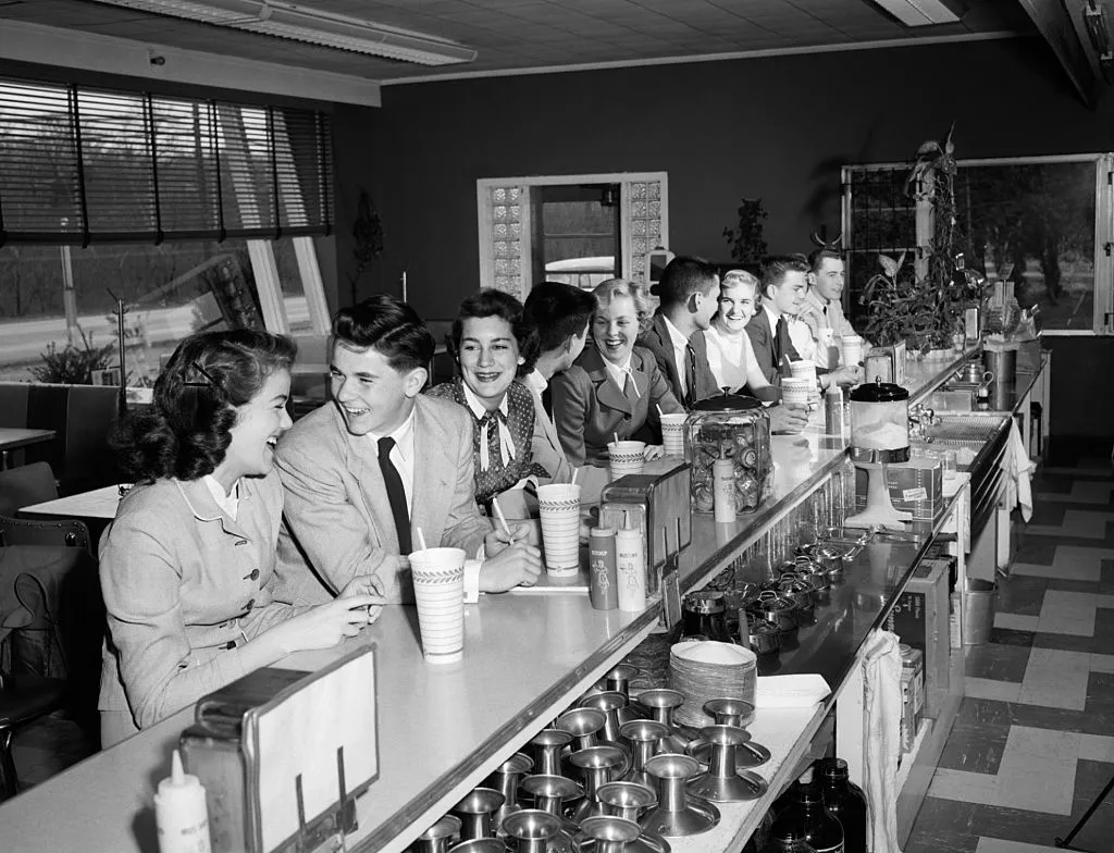Teens sitting at a soda fountain bar 