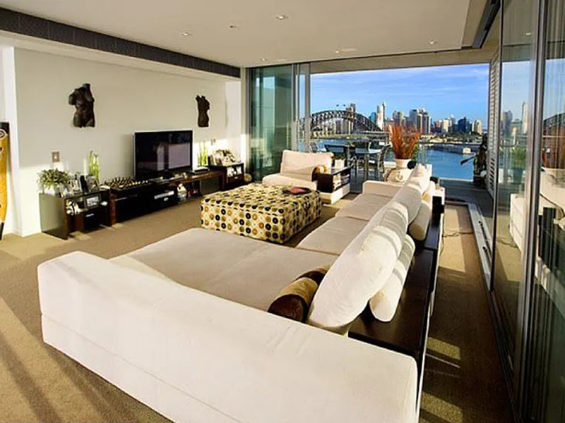A large living space on the top floor of a skyscraper overlooks the Sydney Harbor Bridge