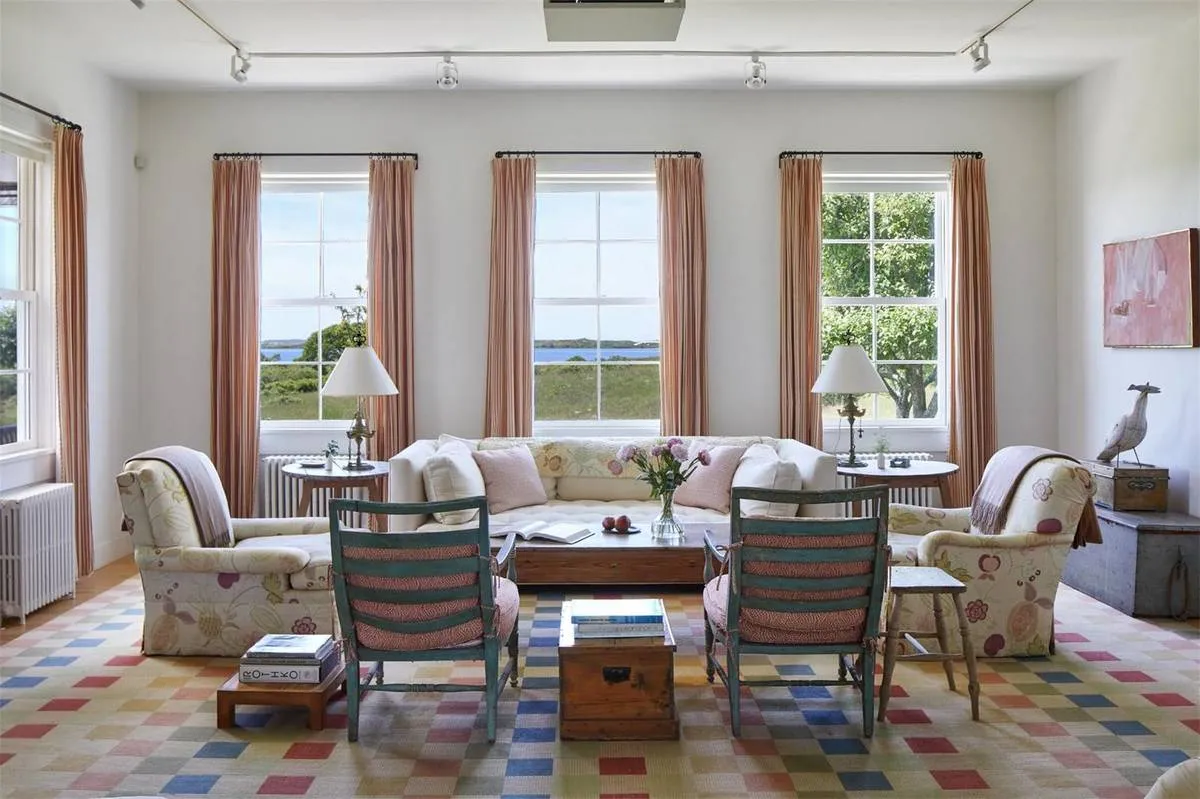 A colorful seating area is arranged before several large windows