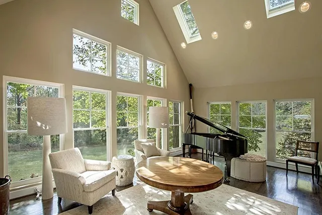 The bonus space off the living room showcases high ceilings, windows and skylights, a piano and sitting space