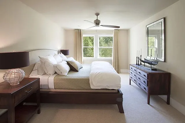 A guest suite fits large bedroom furniture and leads to a window with vivid trees beyond