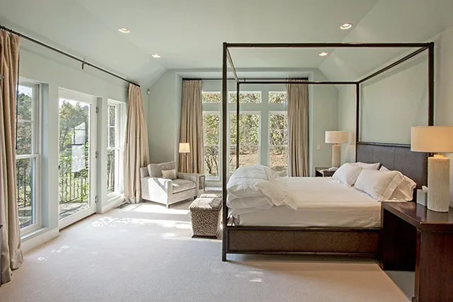 The master bedroom has ample space, tones of windows, and a balcony