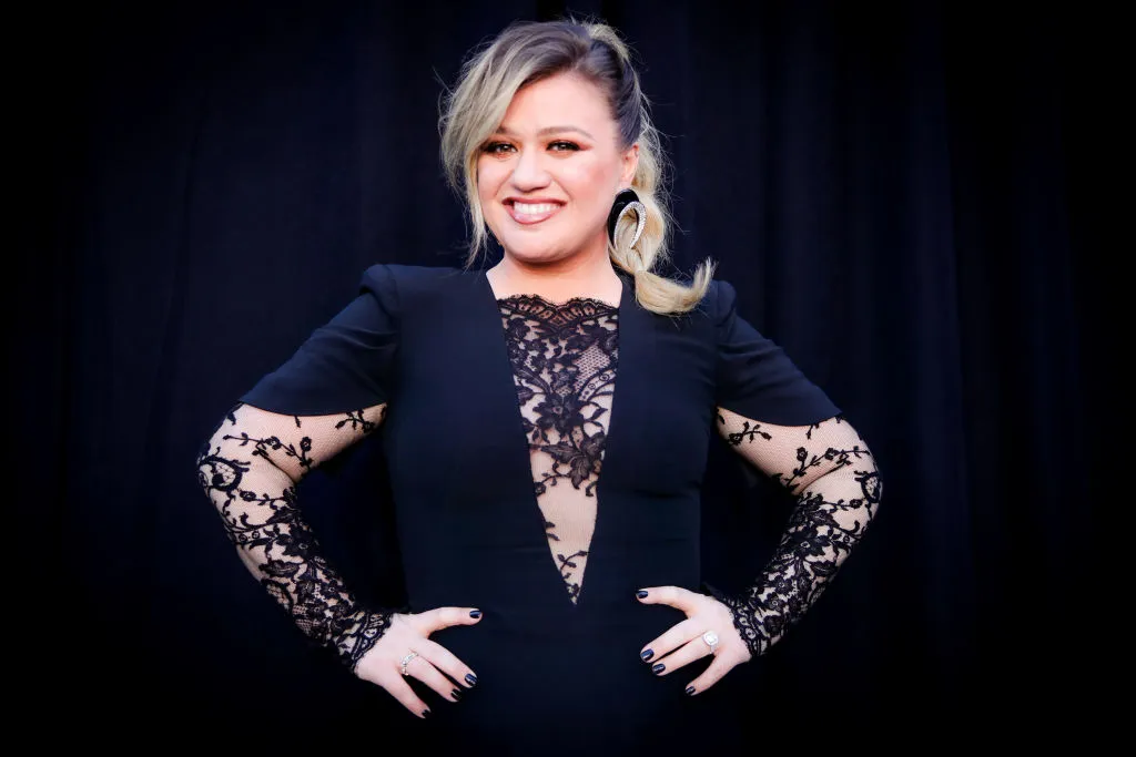 Kelly Clarkson Poses In Front Of A Black Curtain