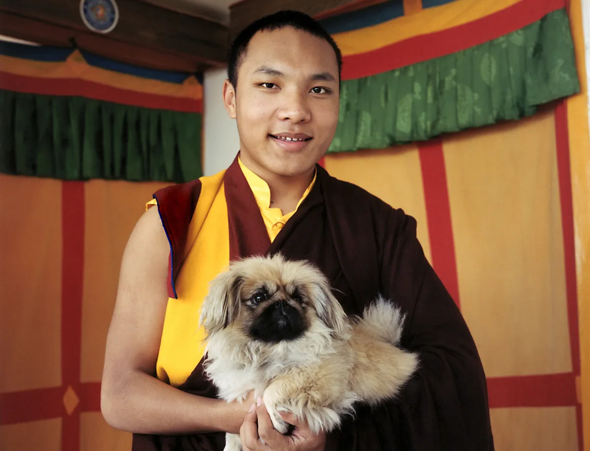 Monk holds his pekinese dog Dekyi