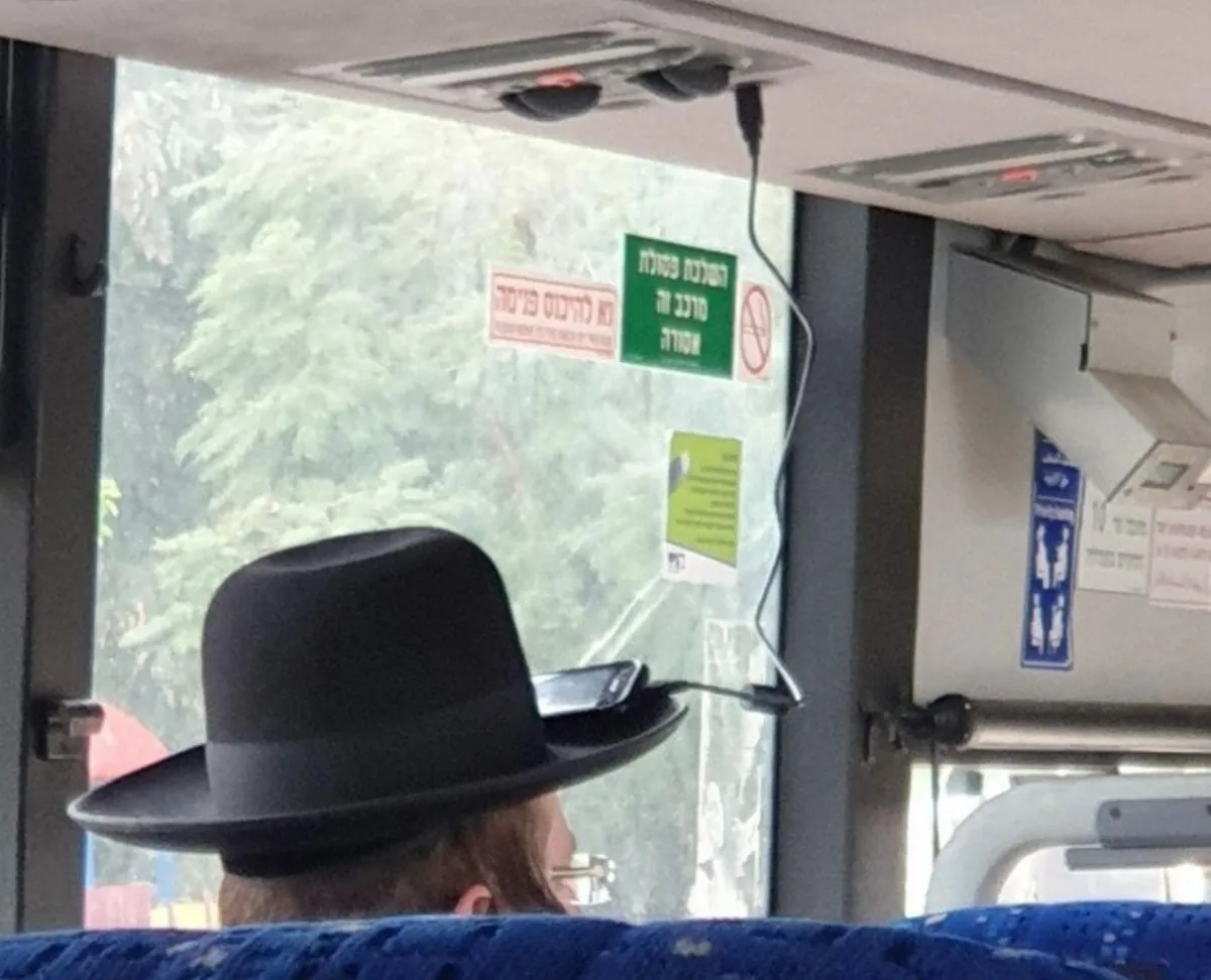 man uses hat brim to hold phone close to charing port