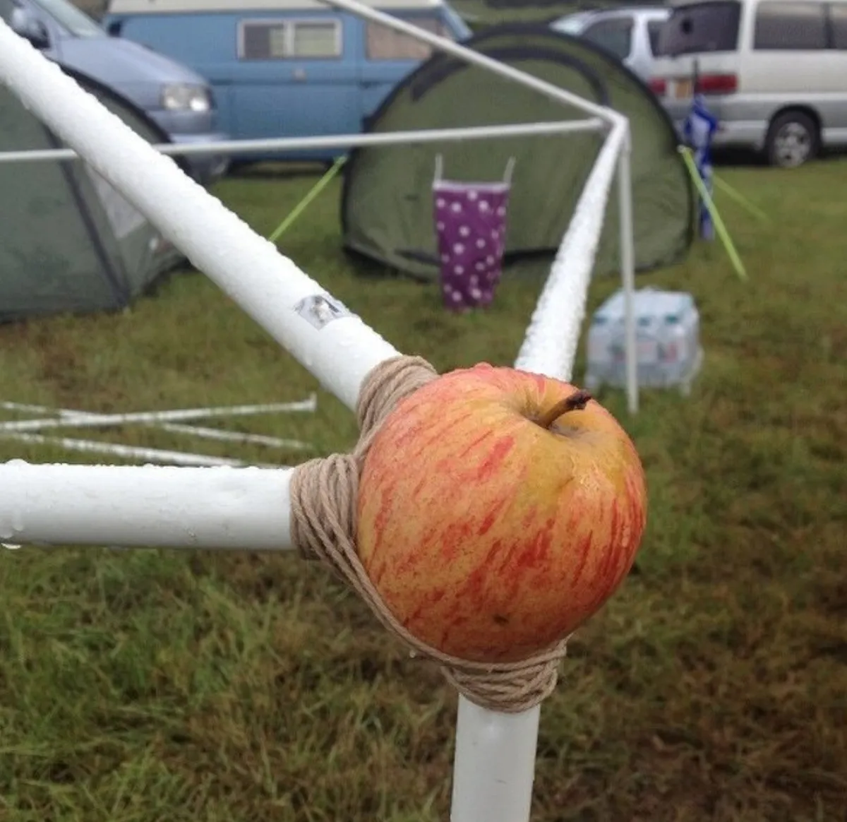 person uses apple to hold tent corner together