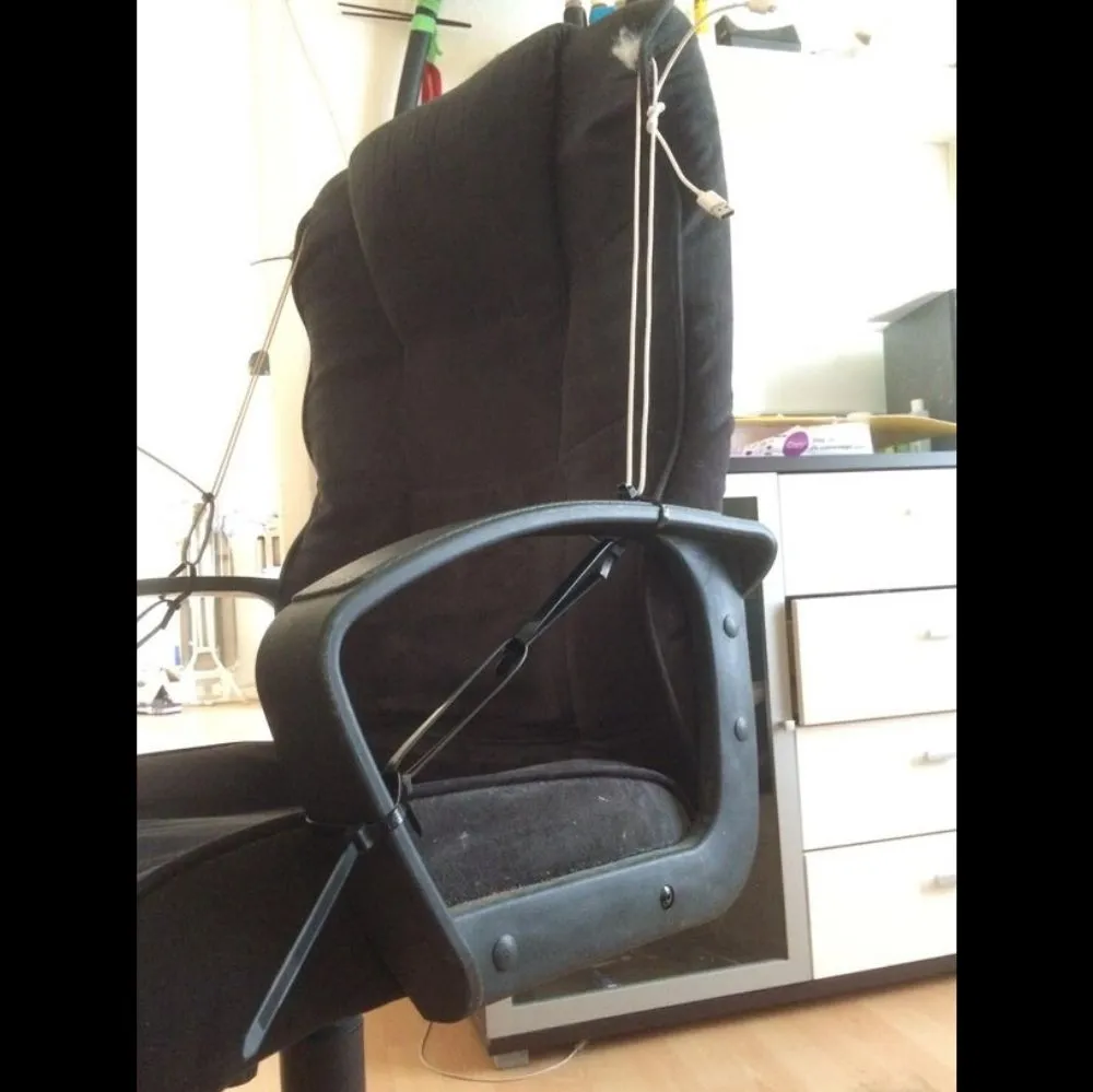 person holds chair back up with a mixture of charging cords and zip ties