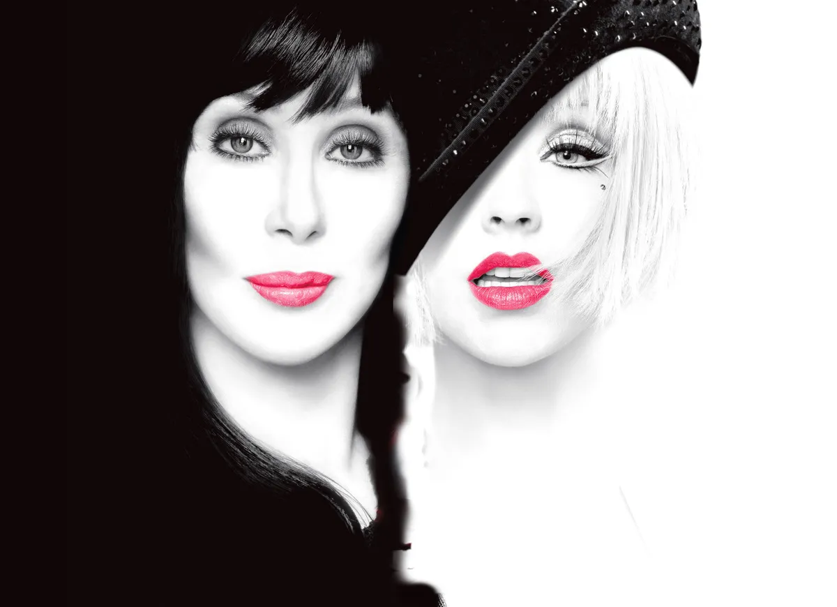 Cher and Christina Aguilera are photographed close up and next to one another in black and white with pink lipstick.