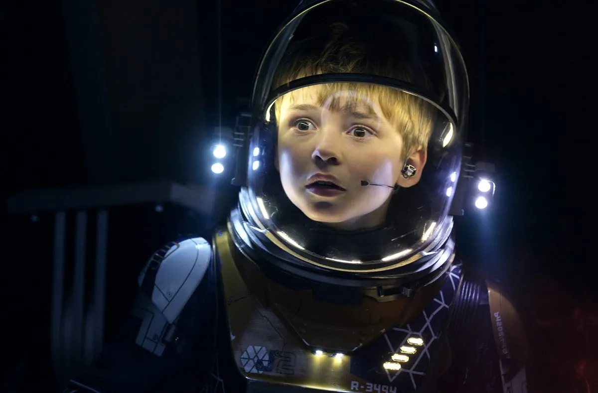 A boy in a spacesuit looks worried.