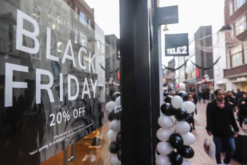 People seen walking by a Black Friday signs with discounts