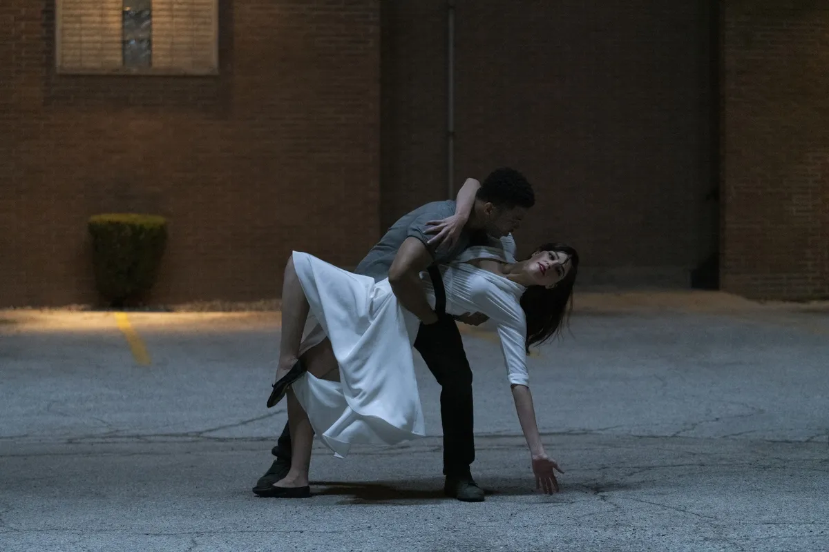 A man dips a woman as they dance outside at night.