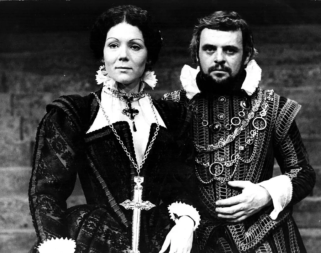 Anthony stands next to a female actor onstage while dressed in medieval attire.