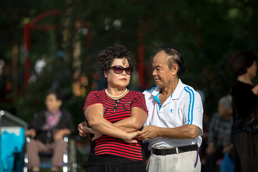 A retired couple dances in the street.