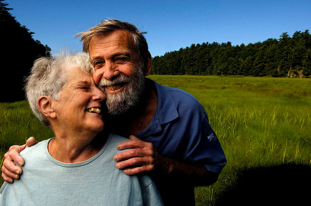 An elderly couple smiles and pose close together.