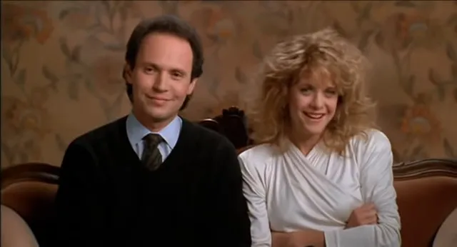 Harry and Sally sit on a coach smiling while being interviewed.