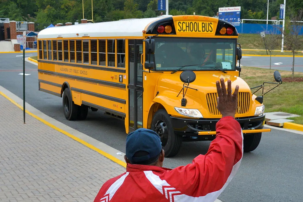 a parent waving to a school bus