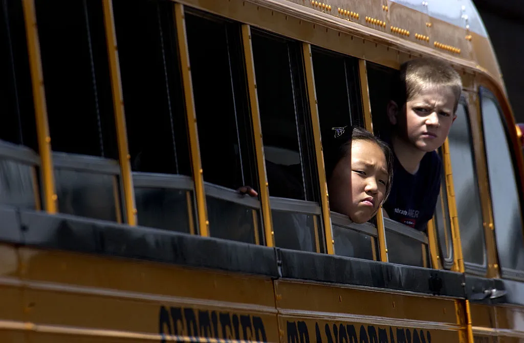 kids sticking their heads out of the school bus