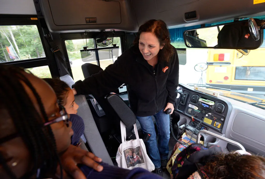 a school bus driver greeting new students