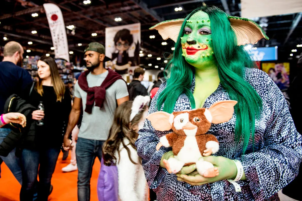 a woman dressed as a gremlin holding a stuffed animal from gremlins