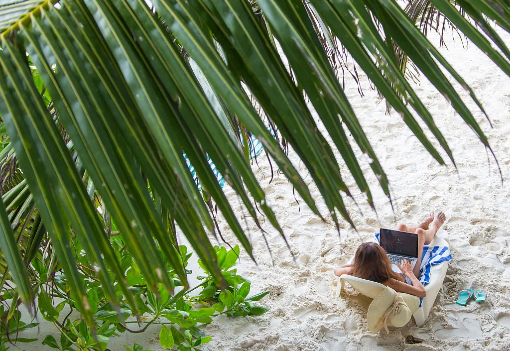 a woman on the beach working on her laptop