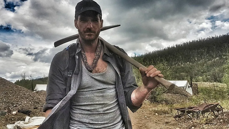 Dan Snow carries a pick axe through Canada in the show Operation Gold Rush.