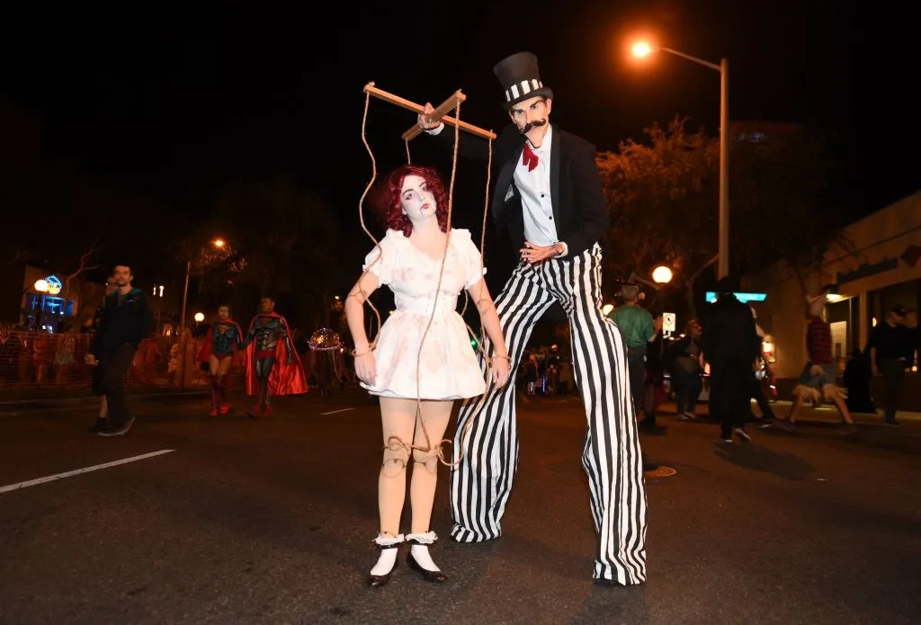 a woman dressed as a puppet next to a guy in stilts
