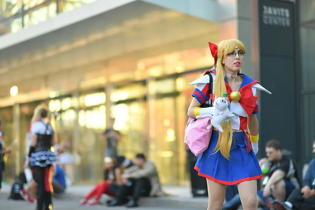 a woman dressed as sailor moon holding a stuffed animal cat