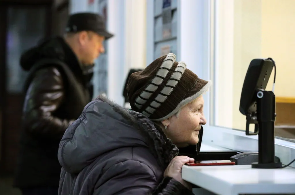 an elderly woman buying something at a ticket counter
