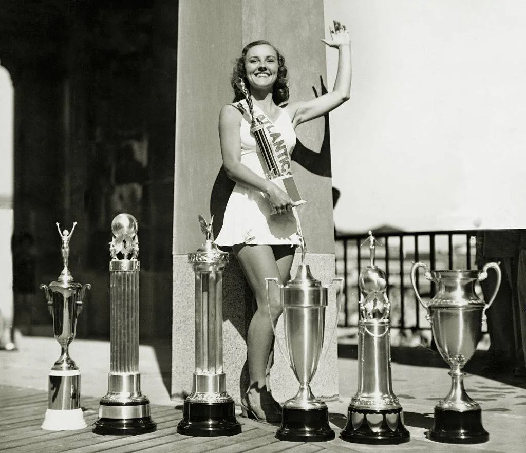 a winner of a 20th century pageant waving with her trophies