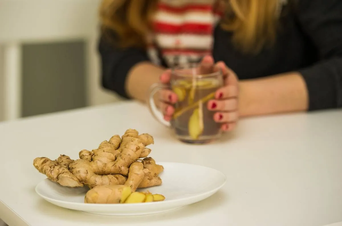 A woman makes ginger tea with fresh ginger laid out on the table.