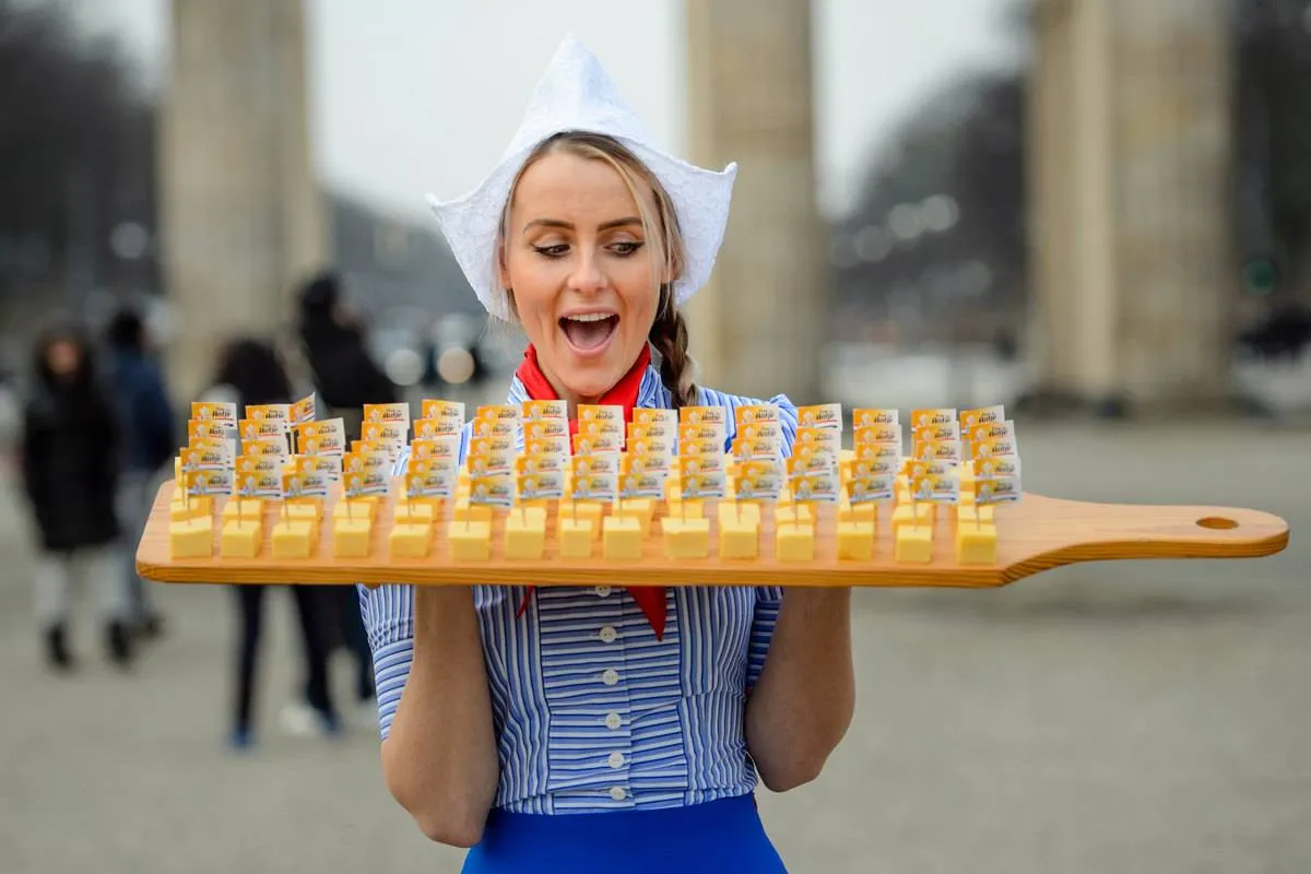 A woman holds an enormous Dutch cheese platter.