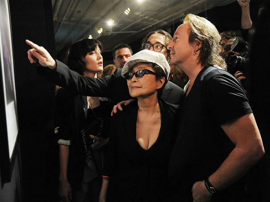 Sean, Julian, and Yoko crowd together to view a photo at Julian's exhibition.