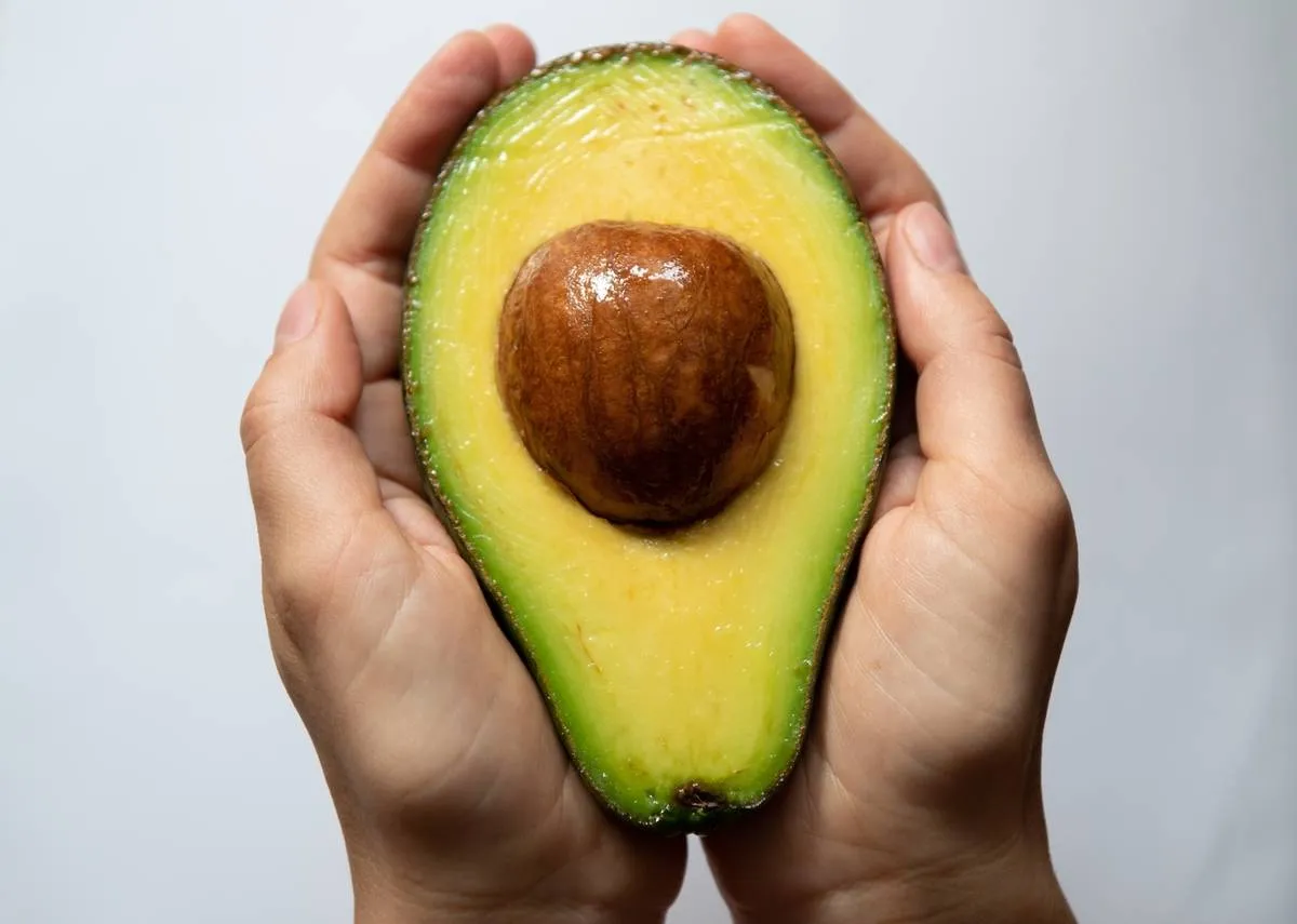 A person holds an avocado half.